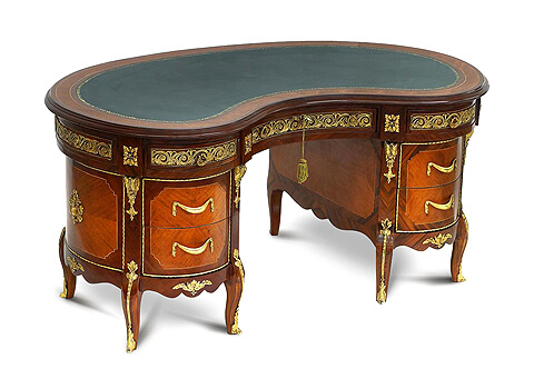 A French Transitional style ormolu-mounted and veneer inlaid kidney shaped seven drawers desk, The gilt-tooled inset kidney shaped leather top within a beveled border surface above a frieze with three drawers ornate with heavy ormolu guilloche pattern and lyre shape ormolu handles separated by blocks ornamented with ormolu rosettes, The fine sans traverse veneer inlaid lower part houses four deep drawers framed in ormolu band and drape shaped ormolu handles on each drawer, Each corner decorated with shaped chutes of ormolu acanthus volute bracket, Below each lower drawer a scalloped shaped frieze ornamented with foliate design ormolu mount, The beautiful short cabriole eight legs are beautiful ornamented with fine chiseled foliate ormolu mounts elongated with ormolu strip to the ormolu sabots