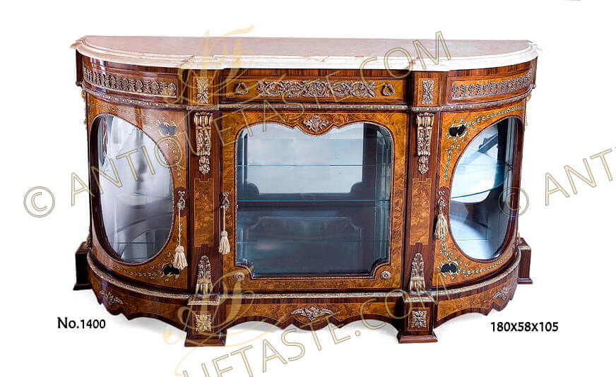 A grand French 19th century Napoleon III style distressed ormolu-mounted D-shaped exotic veneer and marquetry inlaid display sideboard | Credenza, The breakfront beveled marble top rests above a reversed frieze with central large drawer ornamented with Rinceau Guilloche style ormolu and lyre shaped ormolu handles between two prominent blocks adorned with ormolu rosettes, the flanking curved faux drawers decorated with ormolu works or repeated Anthemions and Palmettes, all above a Bead-and-Real ormolu trim surround, The central part with a shaped ormolu-mounted glazed paneled door between separating block adorned with ormolu acanthus volute brackets. The rounded sides with curved cupboard shaped glazed doors marquetry inlaid with laurel foliage and Coromandel patterns. All doors with ormolu keyhole escutcheon, Below is a Leaf-and-Dart ormolu band rests on D shaped plinth ornamented with foliate ormolu mounts and four protruding blocks with ormolu rosettes