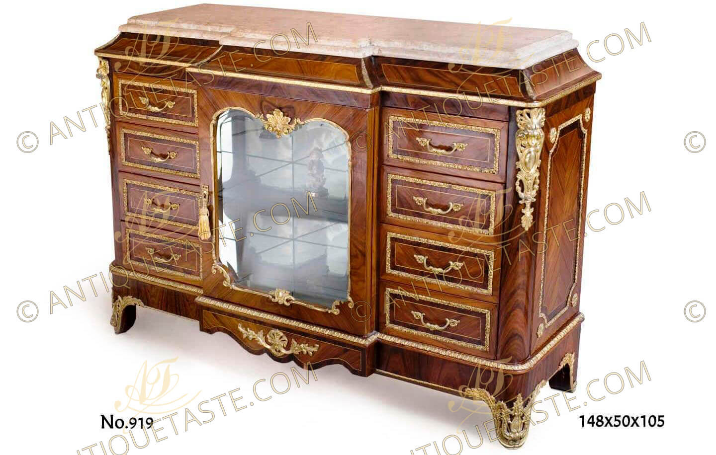 A fine Transitional style gilt-ormolu-mounted veneer-Inlaid Cartonnier with beveled breakfront marble top above a concave frieze and gilt-ormolu trim, the cabinet is centered by a shallow breakfront cupboard glass door with a glass shelf framed by a gilt-ormolu encadrement with a fine cast gilt-ormolu foliage ornamentation flanked by eight drawers, four drawers to each side cornered by fine chiseled  gilt ormolu foliate mounts, raised on a shaped plinth headed with an ormolu trim inlaid with gilt ormolu foliate sabots on the built-in legs
