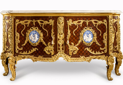 French late 19th century Louis XV Regence style gilt-ormolu-mounted and parquetry veneer inlaid commode a vantaux after the model Commode Médaillier designed by the Slodtz brothers and executed by Antoine-Robert Gaudreaux, made for le cabinet du Roi at Versailles with a serpentine veined moulded marble top above a pair of doors with one tier inside, each door centered by an ormolu oval one with a cherub and goat, the other oval with Ariadne on a leopard, all within marvelously chiseled ribbon-tied acanthus leaves and blossoming flower swaging garlands, all on a diamond parquetry ground veneer inlay centered by an ormolu female mask on scrolling ormolu works and shell on a very fine ormolu scalloped shell form apron with acanthus leaves scrolls, the sides each with a further similar oval medallion within the same ormolu tied scrolling frame, and raised on astonishingly chiseled and burnished ormolu cabriole legs with scrolled ram-headed capitals