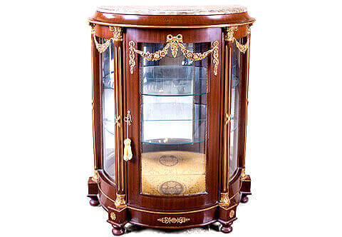 Demilune shape French Neoclassical style ormolu-mounted Cabinet-Vitrin, surmounted by a shaped marble top and ornamented with ormolu ribbon-tied floral blossoming garlands and flanked to the four corners by gilt-fluted columns supports with an ormolu Corinthian capitals and resting on ball feet. Available per request with upholstered tufted back or mirror back as displayed