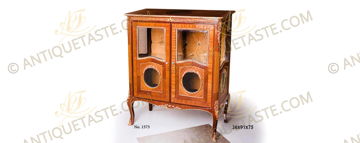 A fine French Louis XV style ormolu-mounted sans traverse veneer inlaid Display Cabinet; resting on handsome ormolu mounted cabriole legs; the interior upper half is upholstered in capitonné style, the lower half of the door is adorned with an oval medallion encircled with ormolu floral motifs and closed by pierced ormolu gallery