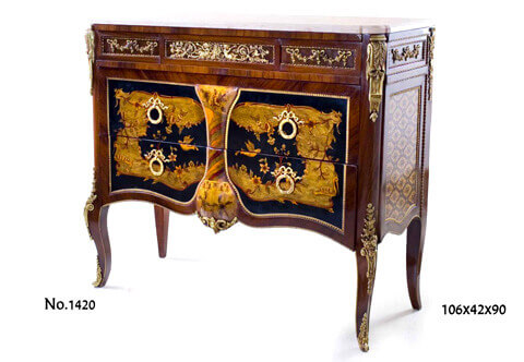 French Louis XV ormolu-mounted parquetry inlaid Chinoiserie style commode, 
The eared marble topped above a conforming frieze with central drawers ornamented with intricate and pierced ormolu mount with two cherubs blowing trumpet amidst foliate and scrolled movements, flanked by two faux drawers decorated with ribbon tied festoons, all within a twisted ormolu borders, Below are two large deep drawers with sans traverse Chinoiserie style scene of lake, swans, flying birds and gardens, with ribbon tied ring handles and dentil ormolu border, separated by a central inflated part with foliage marquetry pattern terminating with pierced ormolu cabuchon with foliate scrolled mount, The cut corners display on top a fine and richly chiseled ormolu mounts of acanthus volute on drapes hung on fluted façade above a pine cone, the lower part adorned with a magnificent large ormolu mount of blossoming flower bouquet on volute chutes rest on the cabriole leg hip, The sides with a repeated upper ormolu design as the forepart above a diamond parquetry pattern with flower rosettes, The lower contour of the commode with a beaded ormolu band runs on the cabriole legs that terminate with detailed foliate ormolu cast turned sabots
