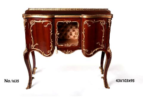 French Louis xv style ormolu-mounted serpentine shape display cabinet on the manner of Francois linke and Léon Messagé late 19th century, in reddish brown, topped with ormolu open work border above a recess central display door richly cast gilt-ormolu waterfall issuing scrolling foliate encadrement and upholstered inside with silk fabric in tufting / capitonné style, with two doors to each side beautifully ornamented with scrolling shell issuing scrolling foliage encadrement on the Leon Message manner. The exquisite cabinet is cornered with acanthus ormolu mounts and raised on splayed cabriole legs applied with ormolu foliate sabots