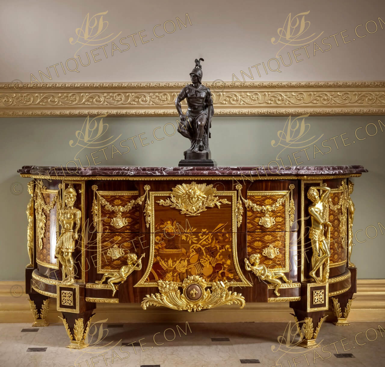 A French ormolu-mounted marquetry and parquetry D shaped commode, after the model by Jean-Henri Riesener, Circa 1890, surmounted by a shaped and stepped veined marble top, centered to the front by a pair of drawers headed by a sunburst winged mask ormolu mount, with central panel inlaid sans traverse with an ewer and basket of fruit and flowers flanked on each side by cherubs emblematic of Bienfaisance and Justice, above a fleur-de-lys-studded ormolu globe and cornucopia, flanked to each side by inlaid parquetry cupboard door hung with floral swags and ribbon-suspended military trophies, the angles mounted with imitation of the four armorial emblematic of Courage, Force, Prudence and Tempérence, on tapering acanthus-mounted feet