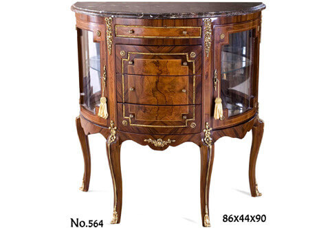 A decorative French Louis 15th style ormolu-mounted Demilune shaped Display Cabinet; veneer inlaid in two types of veneers, surmounted with a beveled marble top, with two doors and four drawers, decorated with ribbon tied blossoming chutes, ormolu moulded encadrements and ormolu sabots