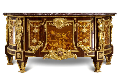Jean-Henri Riesener commode, a French ormolu-mounted marquetry and parquetry D shaped commode, after the model by Jean-Henri Riesener, Circa 1890, surmounted by a shaped and stepped veined marble top, centered to the front by a pair of drawers headed by an sunburst winged mask ormolu mount, with central panel inlaid sans traverse with an ewer and basket of fruit and flowers flanked on each side by cherubs emblematic of Bienfaisance and Justice, above a fleur-de-lys-studded ormolu globe and cornucopia, flanked to each side by inlaid parquetry cupboard door hung with floral swags and ribbon-suspended military trophies, the angles mounted with imitation of the four armorial emblematic of Courage, Force, Prudence and Tempérence, on tapering acanthus-mounted feet