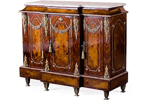 Meuble A Hauteur D'appui, A most elegant late 19th century French Transitional style veneer inlaid three doors meuble à hauteur d'appui , The breakfront moulded marble top above a conforming mahogany veneer inlaid and filet bordered breakfront concave apron with a hammered ormolu band above three doors, the central door elegantly protrudes forward with a central ormolu cabochon amidst the other two doors, all doors quarter sans traverse palisander veneer inlaid, centered with mahogany veneer inlay within filet and ormolu beaded encadrement with flower rosettes, topped with  impressive blossoming swaging festoons and flanked with richly chased chutes ormolu mounts of acanthus, wreaths and imbricated foliage, the sides have the same design, All above a breakfront veneer inlaid protrusive plinth topped with a Cyma Recta style ormolu trim on ormolu leafy tapering feet