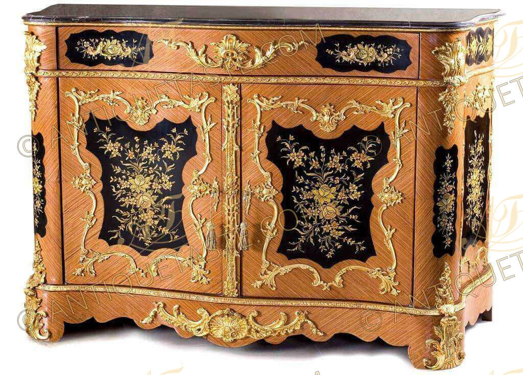 Enchanting Napoleon III style ormolu-mounted veneer inlaid and hand painted side cabinet, after the model Circa 1860, surmounted by a serpentine stepped black marble top above a frieze ormolu band large drawer centered by foliate acanthus mount, flanked to each side by a floral painted panel with ormolu foliate handle, above a pair of cupboard doors, each centered by a cartouche with spring flowers with a scroll and foliate frame, the interior fitted with an adjustable shelf, the sides each with conforming panels hand painted as well with flowers, the apron centered by a scroll shell, on shaped feet with foliate clasps