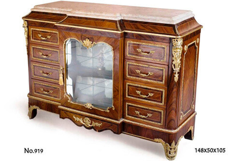 French style cartonnier, A fine Transitional style gilt-ormolu-mounted veneer-Inlaid Cartonnier with beveled breakfront marble top above a concave frieze and gilt-ormolu trim, the cabinet is centered by a protruding breakfront cupboard glass door with a glass shelf framed by a gilt-ormolu encadrement with a fine cast gilt-ormolu foliage ornamentation flanked by eight drawers, four drawers to each side surrounded with rich ormolu encadrement, the body is cornered by fine chiseled large gilt ormolu foliate chutes, raised on a shaped plinth headed with an ormolu trim, the breakfront apron centered by a scroll shell, on shaped feet ornamented with ormolu foliate cartouche clasps