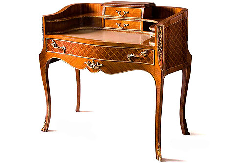 French Napoleon III style ormolu-mounted parquetry inlaid Bonheur De Jour Bureau De Dame, The curve-shaped two shelves back ornamented with a hammered ormolu band centered with two small drawers decorated with a gilt-ormolu strip to the front and drape ormolu band the back, surmounted with a beveled top inlaid with an ormolu strip, Above inset gilt-tooled leather writing surface above a scalloped shaped frieze with a central foliate ormolu mount and housing a wide drawer with two ormolu foliate handles and framed with an ormolu band, The sides, the back and the central wide drawer are inlaid in parquetry style within an ormolu strip, The concave-shaped corners with foliage ormolu mounts within an ormolu band, raised on slender cabriole legs terminated with foliate ormolu sabots