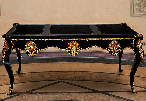 A luxuriant French Louis XV period gilt-ormolu-mounted ebonized wood writing desk, The three sectional inset gilt-tooled leather top cornered with finely chiseled ormolu clasps, The apron below has three scalloped shaped drawers, bordered with hammered foliate ormolu filets in a satin and burnish finish and each drawer is ornamented with a fine cast gilt-ormolu Satyr Mask, The central drawer with ormolu keyhole escutcheon, The desk is raised on four cabriole legs each is topped with gilt-ormolu female busts on foliate chutes body and terminated with ormolu acanthus volute sabots, The sides and back has the same design of the front. The desk is available in other finishing and silvered ormolu casting
