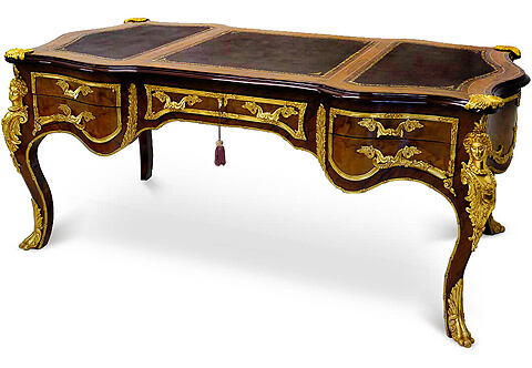 A sensational and grand French 19th century Louis XV style ormolu mounted veneer inlaid five drawers Executive Bureau Plat after a model by Francois Linke, The Bureau Plat is raised on handsome cabriole legs with fine ormolu leafy paw sabots, At each corner are large and impressive ormolu mounts of richly chased maidens and acanthus leaves scrolls, The front scalloped shaped frieze displays five drawers in three sections; each section is framed within an intricate rich foliate ormolu band and exquisite leafy handles, The central recessed drawer has an ormolu keyhole escutcheon with a foliate pattern. Both side drawers are separated by a long acanthus gadroon shaped ormolu chutes extending with ormolu fillet wrapping around the contour of the whole desk, Each side panel is decorated in ormolu band with foliate movements, The back of the desk is finished with three faux drawers that mirror the front. Above is three sectional gilt tooled leather tops within veneer inlaid filet with ormolu lyre foliate seashells clasps at each corner