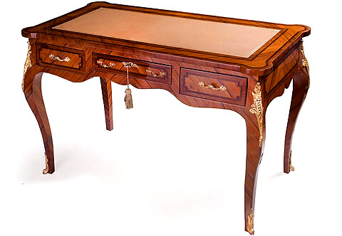 A French Louis XV style ormolu-mounted sans traverse palisander veneer inlaid three drawers Desk, Leather eared top, the surface and the apron with darker veneer filet. The scalloped shaped apron with three drawers ornamented with foliate ormolu handles and foliate ormolu keyhole escutcheon to the central drawer, the desk is raised on cabriole legs topped with fine chased ormolu chutes and ormolu sabots