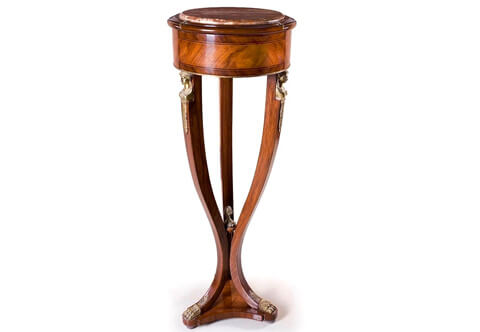 A stunning French 19th century Empire Neoclassical style ormolu-mounted veneer inlaid marble topped Pedestal after the model by of François-Honoré-Georges Jacob-Desmalter; the handsome pedestal is raised by an elegant sans-traverse veneer inlaid triangular base with concave sides on bun feet; the lightly curved supports display robust design, unique and most decorative ormolu paw feet headed with pierced ormolu leaves; the three supports are tied to the bottom with an imitation of a wooden scepter surmounted by an ormolu acorn finial and display at the top striking richly chased ormolu headdress female busts on suspending acanthus leaves. Above is the veneer and double filet inlaid circular tier ornamented to the bottom with a delicate ormolu band and topped with an inset marble top and three ormolu leaves above each support.