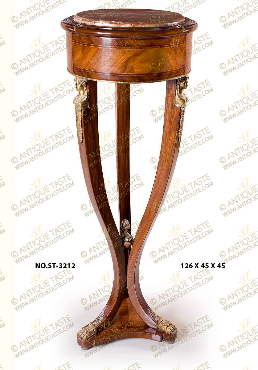 A stunning French 19th century Empire Neoclassical style ormolu-mounted veneer inlaid marble topped Pedestal after the model by of François-Honoré-Georges Jacob-Desmalter; the handsome pedestal is raised by an elegant sans-traverse veneer inlaid triangular base with concave sides on bun feet; the lightly curved supports display robust design, unique and most decorative ormolu paw feet headed with pierced ormolu leaves; the three supports are tied to the bottom with an imitation of a wooden scepter surmounted by an ormolu acorn finial and display at the top striking richly chased ormolu headdress female busts on suspending acanthus leaves. Above is the veneer and double filet inlaid circular tier ornamented to the bottom with a delicate ormolu band and topped with an inset marble top and three ormolu leaves above each support.