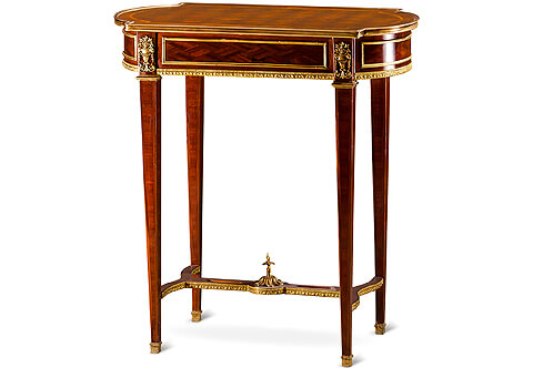 A dignified French mid 19th century Louis XVI Neo-classical style gilt-ormolu-mounted and parquetry inlaid Table À Ouvrage after the mode by Maison Kriéger, The oval breakfront top has a crossbanded veneer and parquetry inlaid within a molded gilt-ormolu gallery above a conforming sectional frieze with one drawer and borders of ormolu filets, separated by block ornamented by Neo-classical style gilt-ormolu mounts of beaded and reeded vase issuing floral Rinceaux style and bouquet of blossoming foliate branches. The apron is bordered to the bottom with exquisitely chased ormolu designed gallery, Raised by slender tapered legs with ormolu trim finished with ormolu sabots and top ormolu crown, The legs are joined by a pierced waved sides stretcher elegantly decorated by a beaded and foliate ormolu trim with a central ormolu foliate movements final
