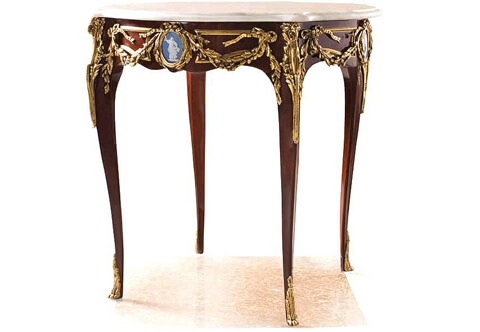 An impressive French Louis XV style ormolu-mounted mahogany inlaid Herculaneum Wedgwood Jasperware plaque center table after the model by Francois Linke, the eared circular marble top above astonishing a frieze ornamented with falling ribbon-tied laurel festoons centered by an oval medallion with a ribbon-tied laurel-cast wreath framing a light blue allegorical Herculaneum Wedgwood Jasperware plaque, the table is raised on cabriole legs each surmounted by a scrolling acanthus clasp, and put down on acanthus-cast paw feet, the fine piece is available with a central ormolu plaque of a playful cherub