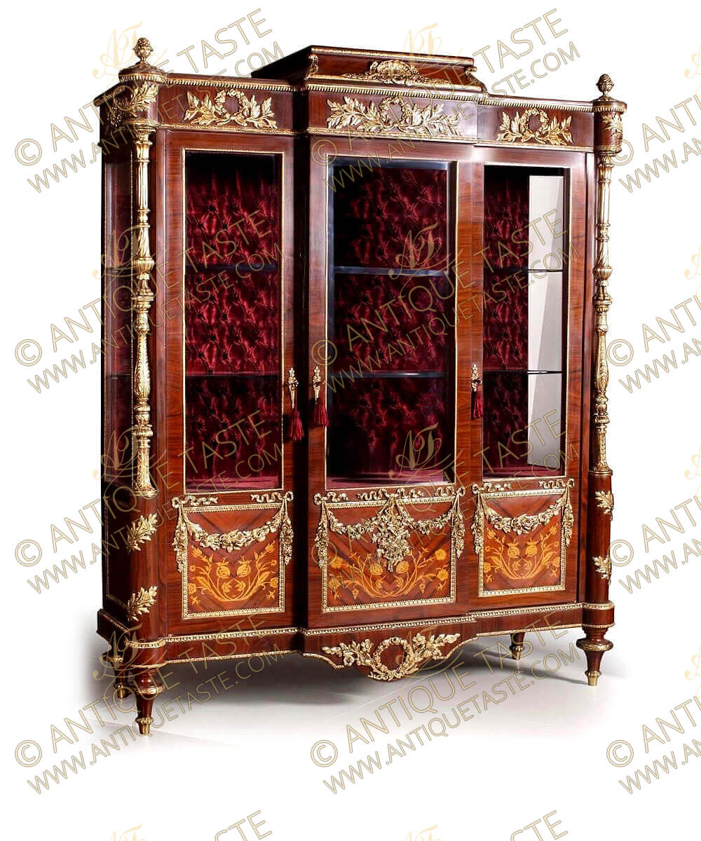A royal French Louis XVI style ormolu-mounted veneer and marquetry inlaid China Cabinet after the model by Frédéric Durand et Fils, based on a model by Martin Carlin, Paris, Last Quarter 19th Century, Crested with ormolu ornamented concave sides crown flanked with ormolu pine cones above an apron bordered with Egg-and-dart pattern ormolu trim adorned with three pierced interlaced swaged loose ribbon-tied laurel garlands above a breakfront body of three glazed ormolu filet bordered three-quarter doors with central protruding door, all have foliate ormolu keyhole escutcheon open to two glazed shelves with velvet fabric capitoné back, The lower quarter sans traverse veneer inlaid and designed with naturalistic flowers marquetry patterns decorated with hung with ormolu blossoming pendant garlands, The sides are similarly decorated, The angles with astonishing gilt-ormolu turned fluted colonnettes angle supports called chinoises surmounted with circular corner with an ormolu laurel leaf and same design continued underneath, all over an arbalette shaped apron centered with an ormolu ribboned-shape blossoming floral wreath and raised on ormolu mounted four toupie feet, The royal finish piece is a part of a dining set